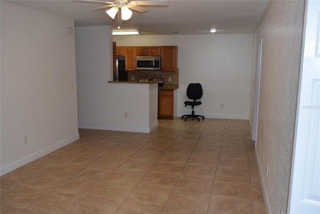 interior space featuring ceiling fan, light tile patterned flooring, and baseboards