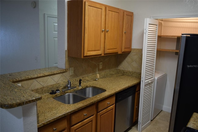 kitchen featuring tasteful backsplash, stone countertops, freestanding refrigerator, a sink, and dishwasher