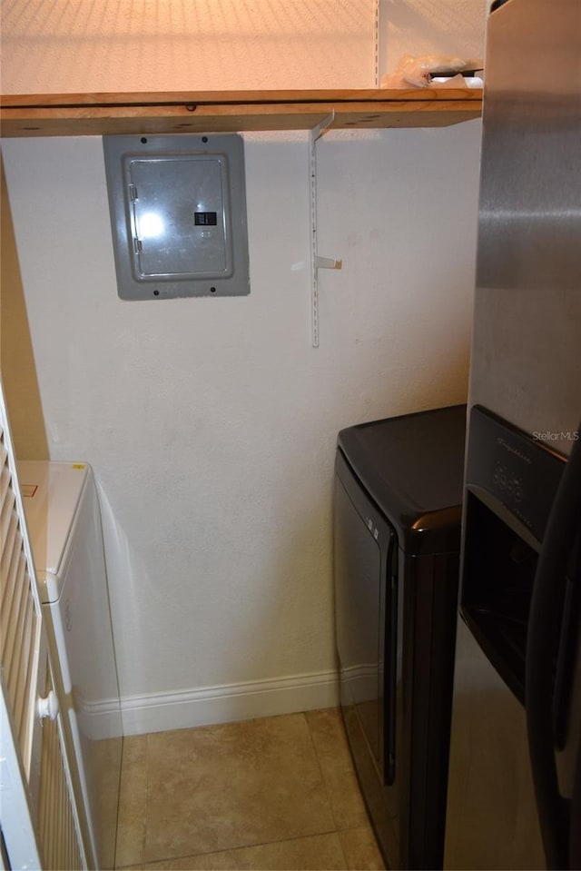 washroom featuring laundry area, light tile patterned floors, electric panel, baseboards, and washing machine and dryer