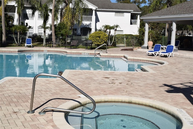 pool featuring a patio, a hot tub, and fence