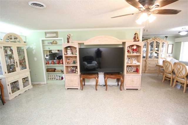 living room featuring ceiling fan, a textured ceiling, and ornamental molding