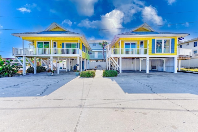 raised beach house featuring covered porch and a carport