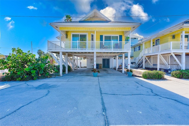 raised beach house featuring covered porch and a carport