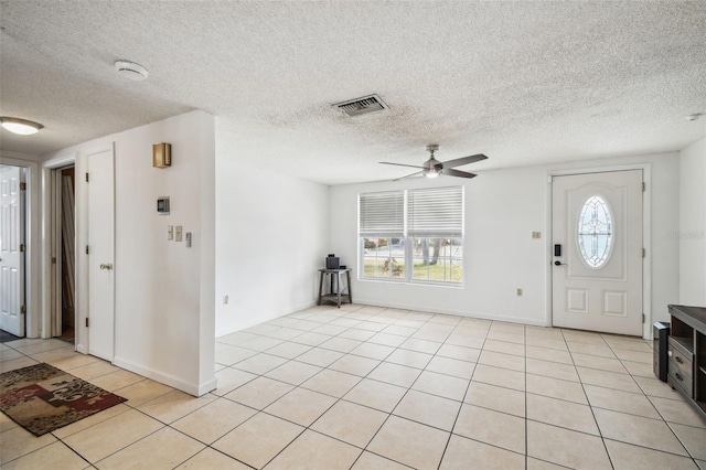 foyer entrance featuring ceiling fan, light tile patterned floors, and a textured ceiling