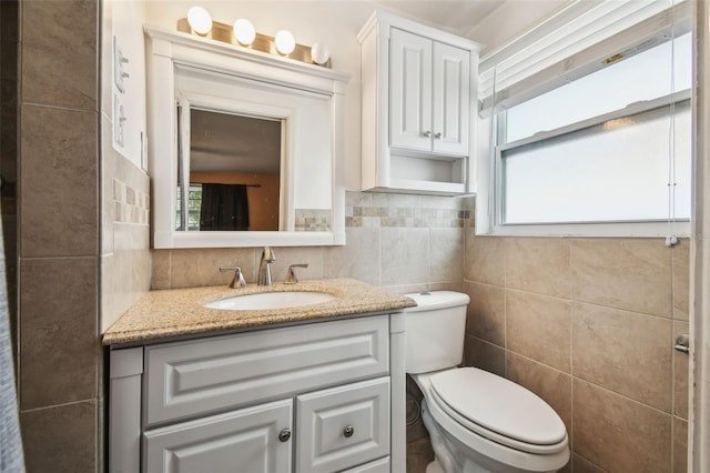 bathroom with vanity, a healthy amount of sunlight, tile walls, and toilet