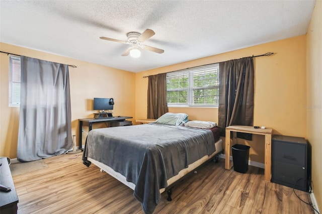 bedroom with hardwood / wood-style flooring, ceiling fan, and a textured ceiling