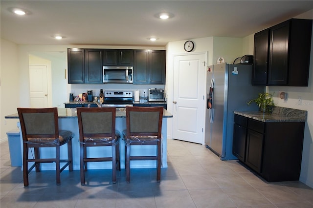 4694 Sigcom Pl, Wildwood, FL 34785 - kitchen with appliances with stainless steel finishes, a breakfast bar, a center island, recessed lighting, and dark stone counters