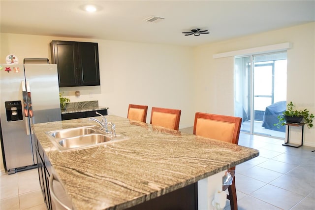 4694 Sigcom Pl, Wildwood, FL 34785 - kitchen featuring stainless steel fridge, a kitchen island with sink, light tile patterned floors, and light stone counters