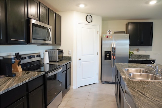 kitchen featuring dark stone counters, sink, appliances with stainless steel finishes, dark brown cabinets, and light tile patterned flooring