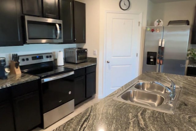 kitchen featuring dark stone countertops, sink, and appliances with stainless steel finishes