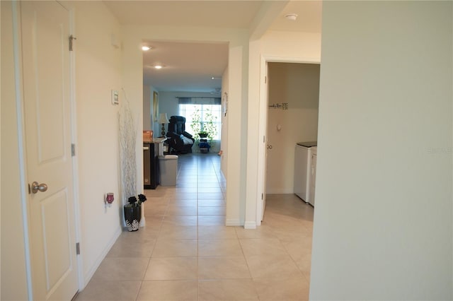 hallway with washer and clothes dryer and light tile patterned floors