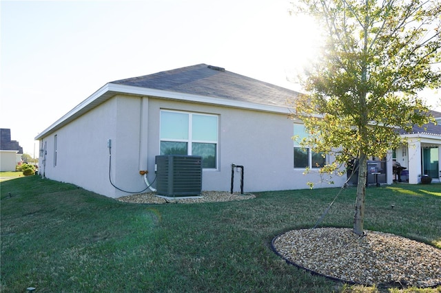 view of side of home featuring a lawn and central AC unit