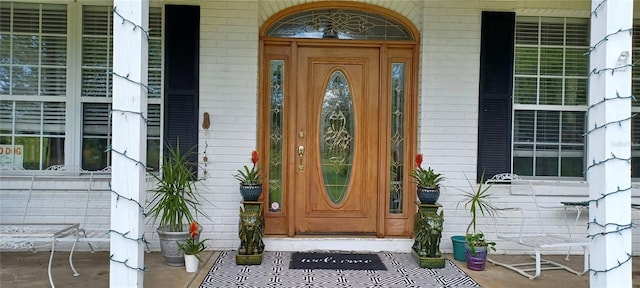 doorway to property featuring covered porch and brick siding