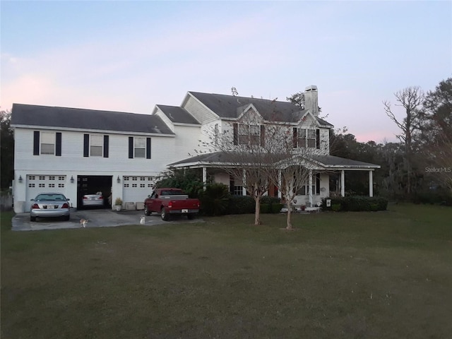 view of front of house featuring driveway, a chimney, an attached garage, and a lawn