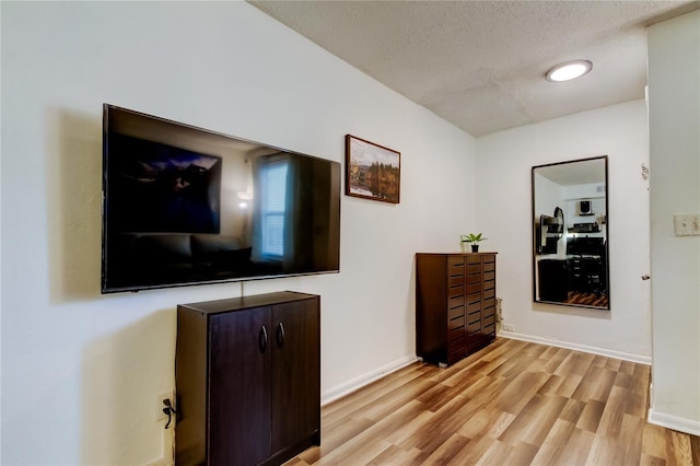 hall with a textured ceiling and light wood-type flooring