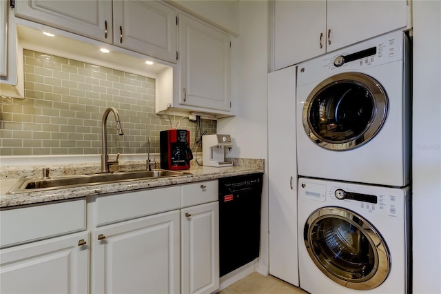 clothes washing area with stacked washing maching and dryer, sink, and light tile patterned floors