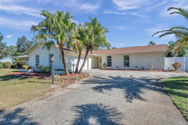 single story home with concrete driveway, an attached garage, and fence