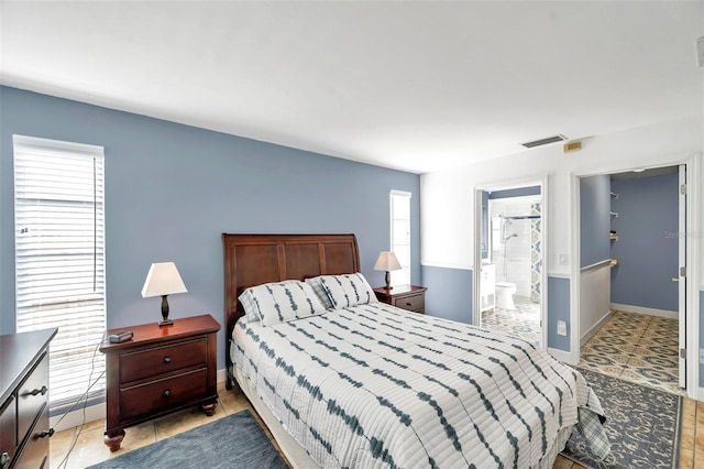 bedroom with light tile patterned floors, multiple windows, and ensuite bath