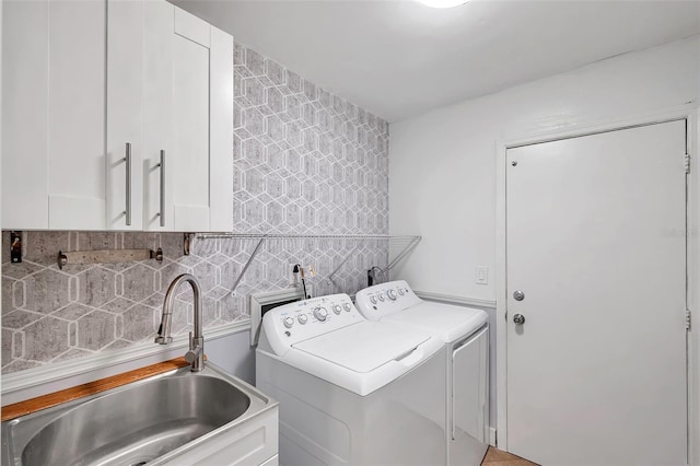 clothes washing area featuring washer and clothes dryer, cabinets, and sink