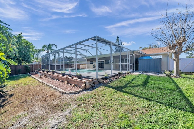 rear view of house with a lanai, a lawn, a fenced in pool, and a storage shed