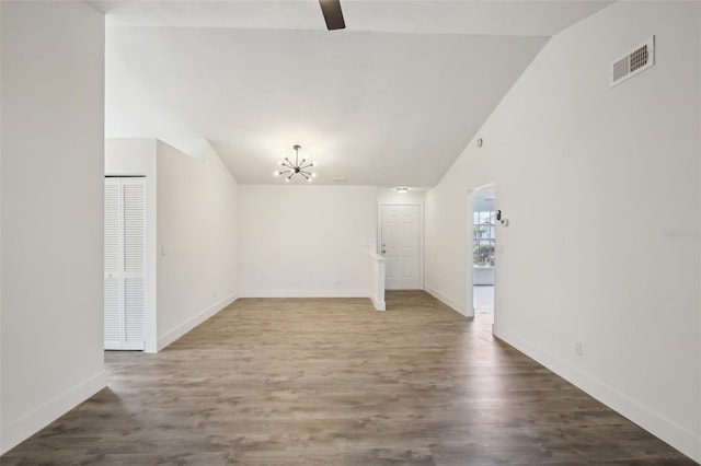 spare room featuring hardwood / wood-style flooring, vaulted ceiling, and a notable chandelier