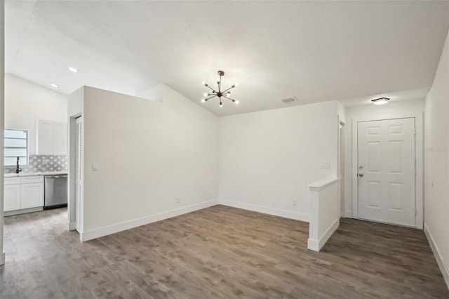 spare room featuring hardwood / wood-style floors, an inviting chandelier, lofted ceiling, and sink