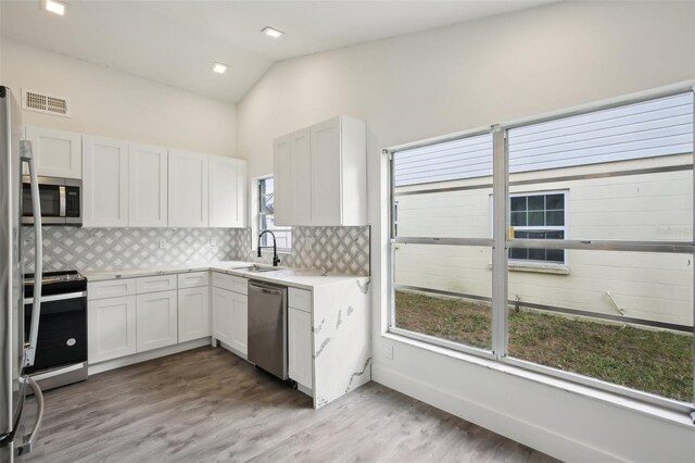 kitchen with white cabinetry, sink, stainless steel appliances, and lofted ceiling