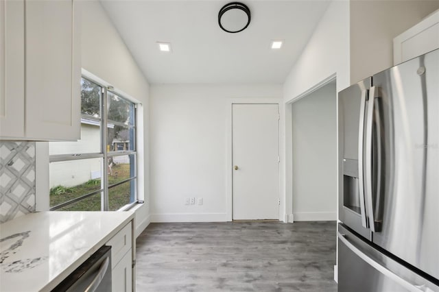 kitchen featuring white cabinets, stainless steel fridge, and vaulted ceiling