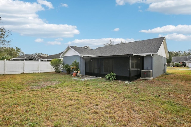 rear view of property featuring central air condition unit, a lawn, and a sunroom