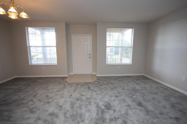 unfurnished room with a chandelier and carpet floors