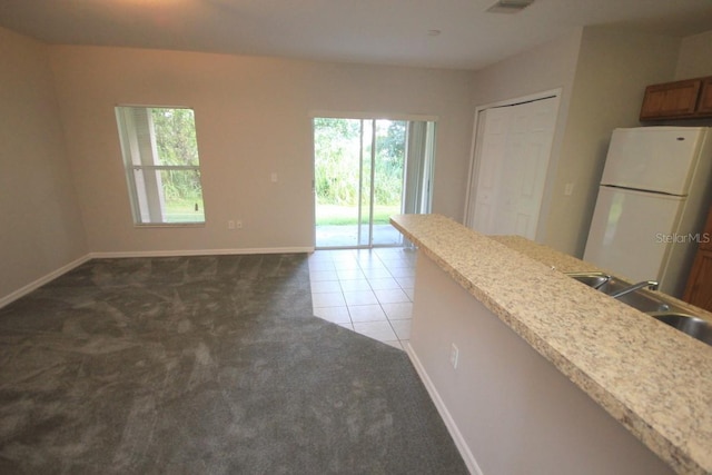 kitchen with sink, light tile patterned flooring, and white refrigerator