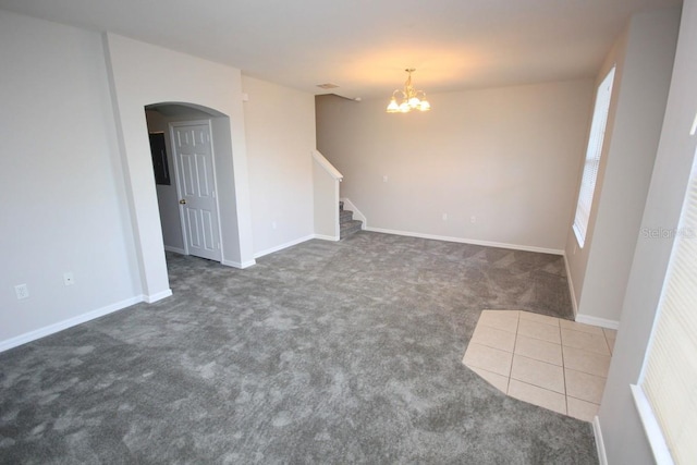 unfurnished living room featuring dark colored carpet and a chandelier