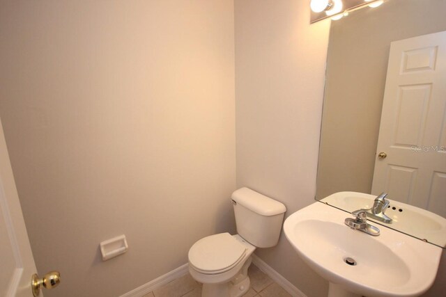 bathroom featuring toilet, sink, and tile patterned flooring