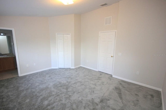 carpeted empty room with vaulted ceiling