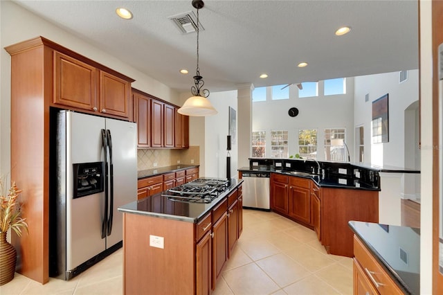 kitchen featuring a center island, stainless steel appliances, backsplash, pendant lighting, and light tile patterned flooring