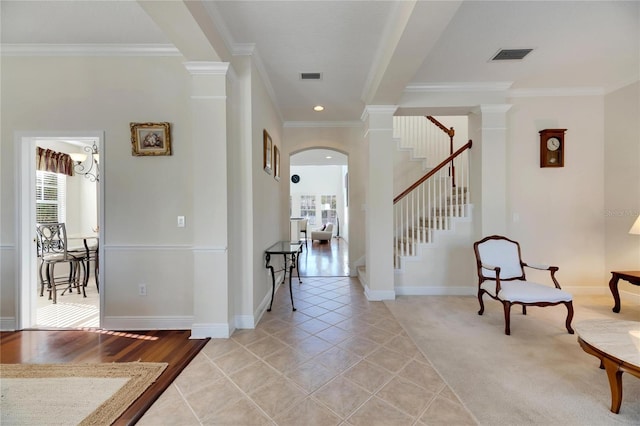 foyer entrance featuring decorative columns, ornamental molding, and light tile patterned flooring