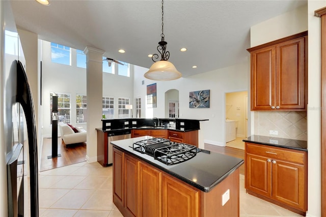 kitchen with decorative light fixtures, a kitchen island, sink, and stainless steel appliances