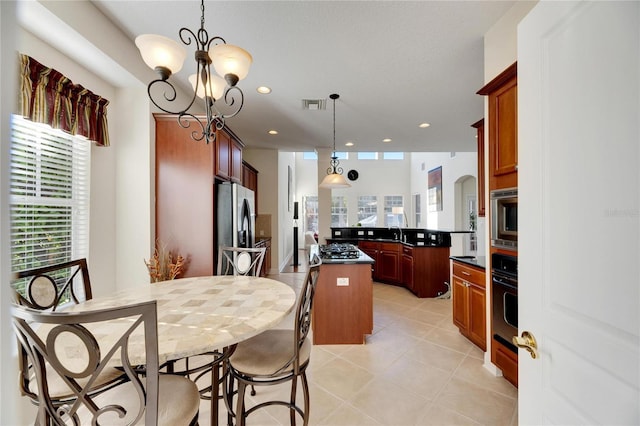 kitchen featuring sink, hanging light fixtures, stainless steel appliances, an inviting chandelier, and a kitchen island