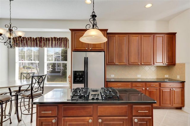 kitchen featuring pendant lighting, a center island, stainless steel refrigerator with ice dispenser, tasteful backsplash, and gas cooktop