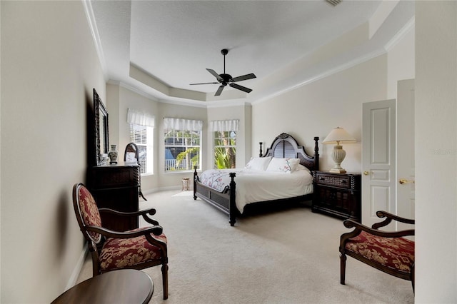 carpeted bedroom with a raised ceiling, ceiling fan, and crown molding