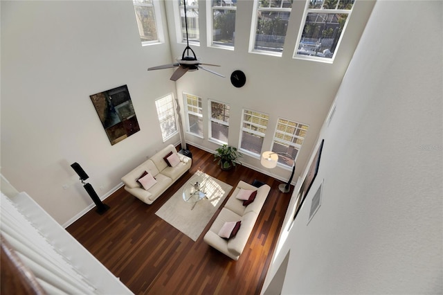 living room featuring ceiling fan, plenty of natural light, a towering ceiling, and dark wood-type flooring