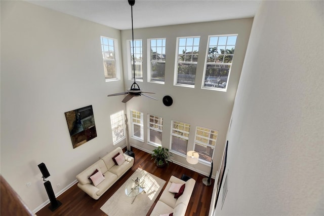 living room with plenty of natural light, dark wood-type flooring, and ceiling fan