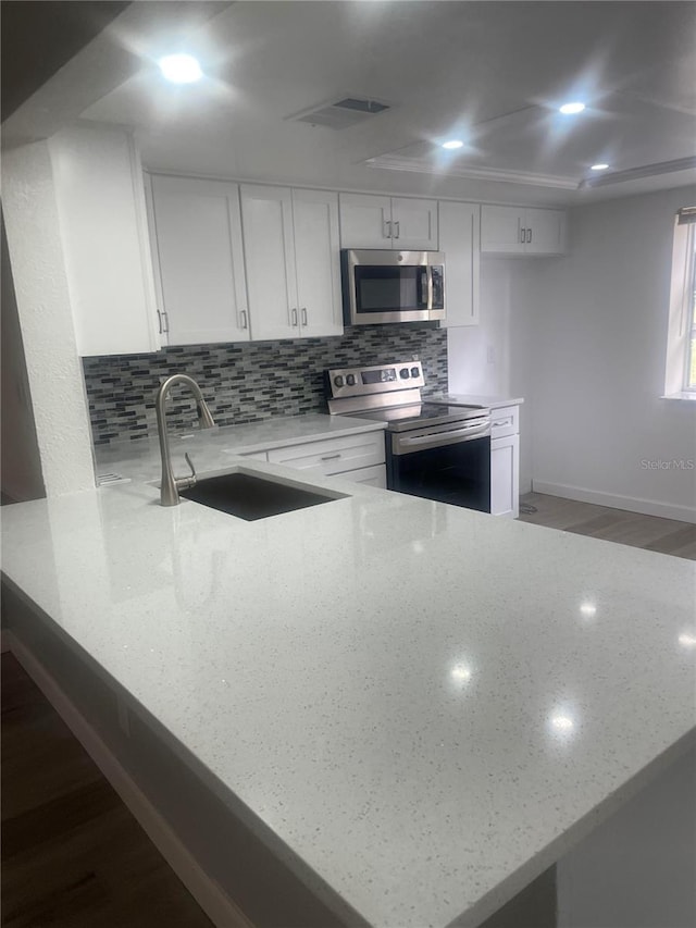 3259 Hilary Cir Unit 1A, Palm Harbor, FL 34684 - kitchen featuring appliances with stainless steel finishes, light stone counters, white cabinets, and backsplash
