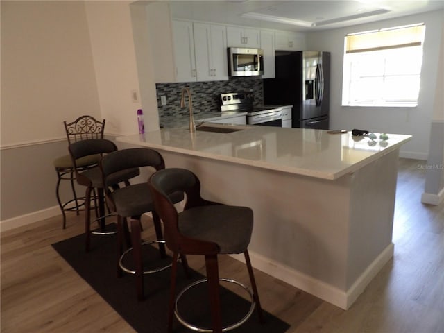 3259 Hilary Cir Unit 1A, Palm Harbor, FL 34684 - kitchen with appliances with stainless steel finishes, a peninsula, decorative backsplash, and wood finished floors