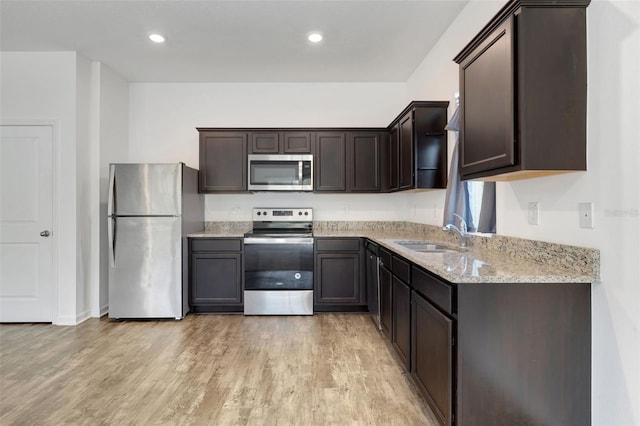 kitchen with sink, light hardwood / wood-style flooring, dark brown cabinets, light stone counters, and stainless steel appliances