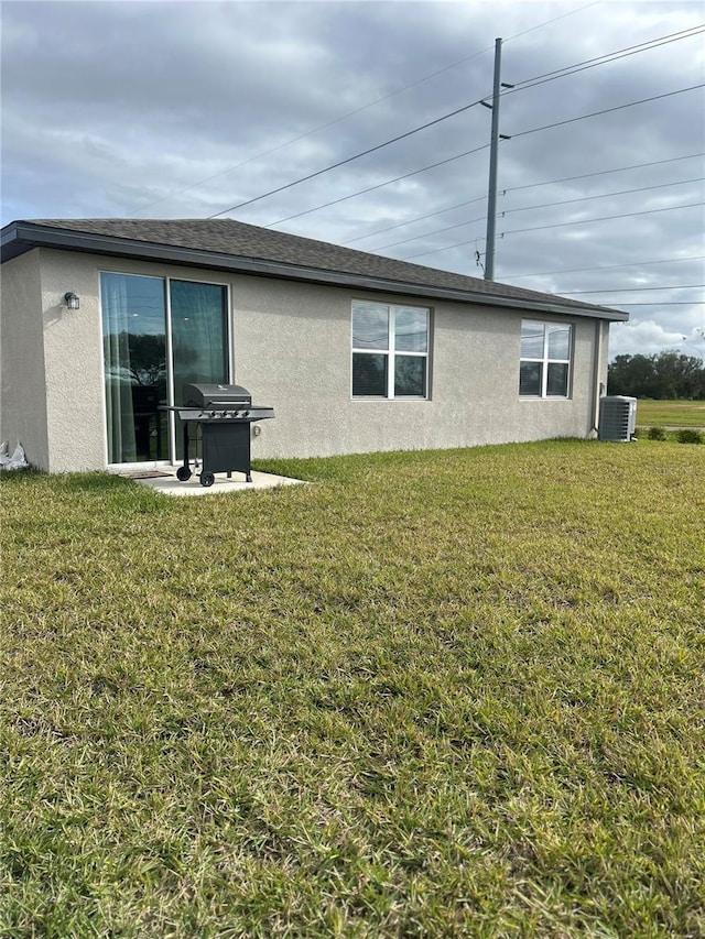 back of property featuring central AC and a lawn