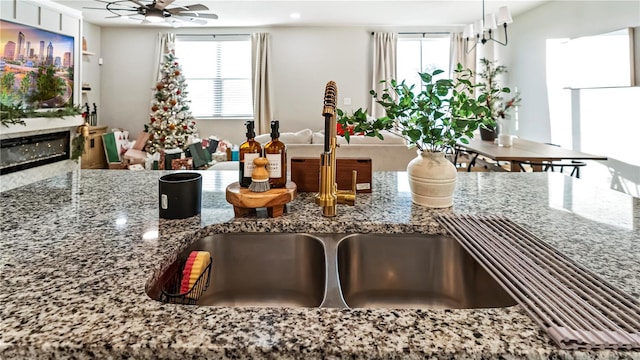 kitchen with ceiling fan, sink, and stone counters