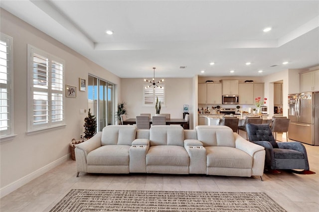 living room with light tile patterned floors, a tray ceiling, and a notable chandelier