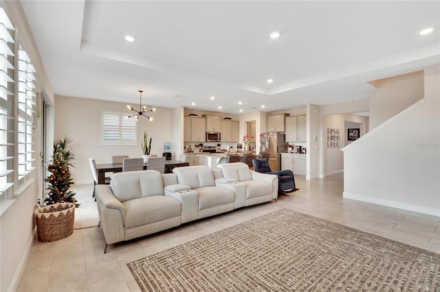 tiled living room with a raised ceiling and a notable chandelier