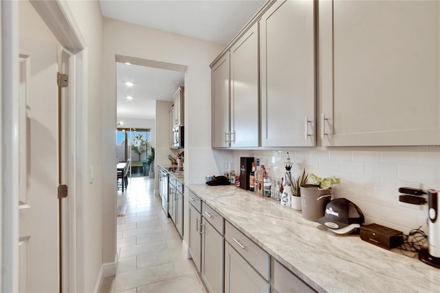 kitchen with light stone countertops, tasteful backsplash, gray cabinetry, and light tile patterned flooring